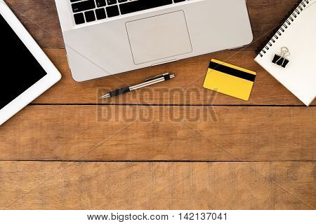 Office desk table with laptop tablet notebook credit card and pen. Top view workspace.