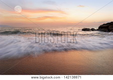 Ocean sunset is a soft pastel colored beach setting with a detailed cloudscape and a gentle wave rolling to shore.
