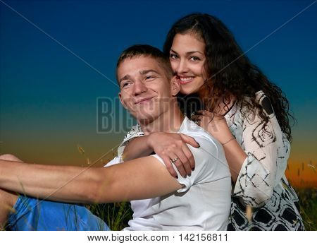 young couple sit on grass and embrace on country outdoor, dark night sky, love concept, romantic people