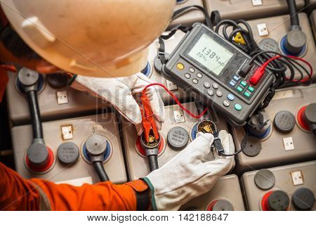 electrician using the digital battery tester to check the resistance and voltage of batteries