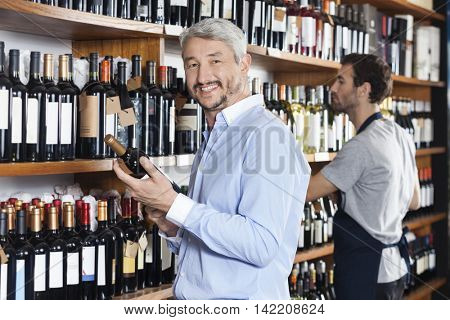 Customer Holding Wine Bottle While Salesman Working In Supermark