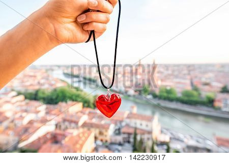 Holding decoration in the form of heart on the italian town Verona background. Verona is famous city of love in the north of Italy.