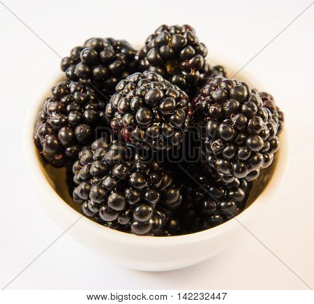 blackberries in a white plate on a white table
