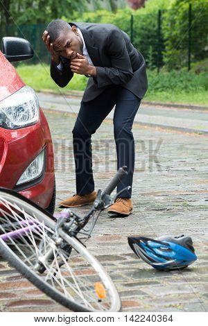 Shocked Male Driver With Hands On Head Looking At Bicycle After Collision On Street