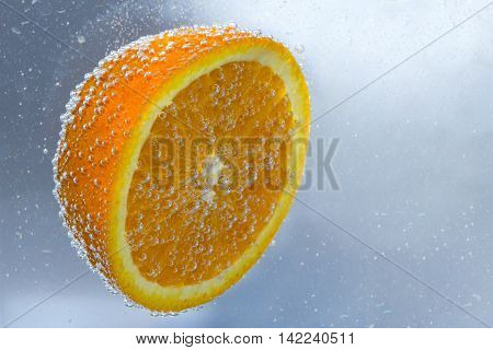 Half of orange in water with bubbles