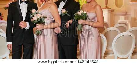 Row of bridesmaids and groomsmans with bouquets at wedding ceremony