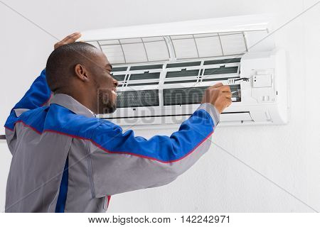 Happy Young African Male Technician Repairing Air Conditioner