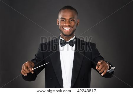 Portrait Of Happy Music Conductor With Baton Against Black Background