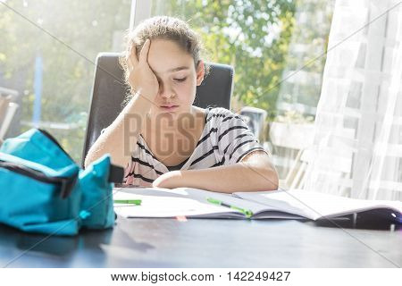 A schoolgirl studying with books on the kitchen table