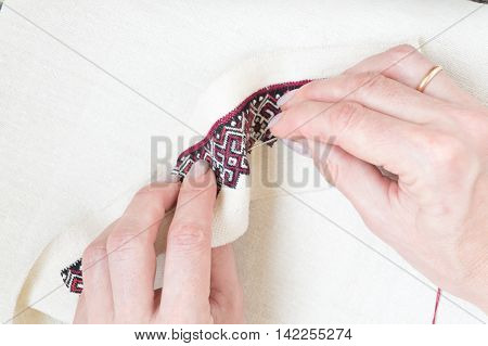 Fragment of embroidery on linen and hands of the master
