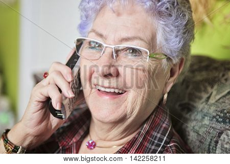 A Portrait of a happy senior woman at home talking on the phone.