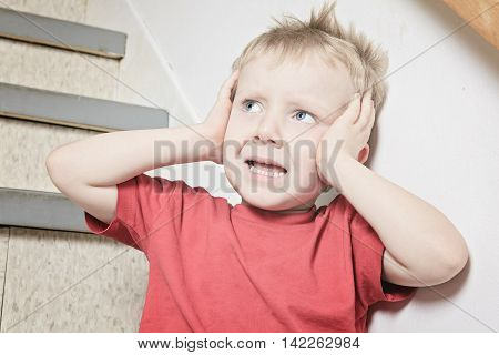 A Neglected lonely child leaning at the wall ear close with his hand