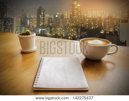Office table with open notebook with blank pages and night building background. Top view. vintage filter effect.selective focus.