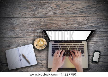 office desk mockup: laptop smart phone and cup of coffee and notebook with business financial graph on wooden background. View above shot. Vintage filter effect.