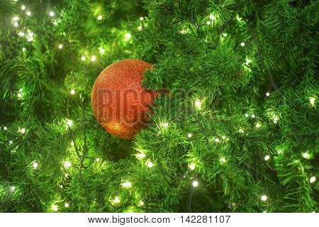 red christmas ball hanging on a christmas tree with little light bulb