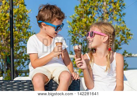 Two happy children eating ice cream near swimming pool at the day time. Concept healthy food.