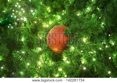red christmas ball hanging on a christmas tree with little light bulb