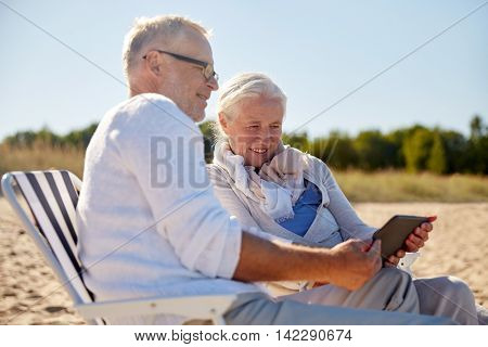 family, age, travel, tourism and people concept - happy senior couple with tablet pc computer resting in folding chairs on summer beach