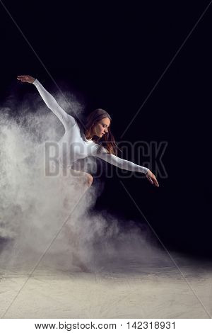 Ballerina dancing with flour on a black background. Dancer in a white bathing suit dancing gracefully with flour. Powder Photo Shoot.