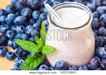 Beautiful appetizer blueberry fruit smoothie milk shake glass jar with juicy fresh berries background top view Yogurt cocktail Natural detox Liquid ice cream hurtleberry huckleberry winberry fraughan