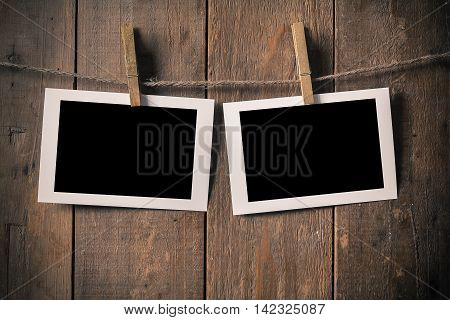 Blank Old Photo Frame Hanging on a Rope By Clothespin on Wood Background