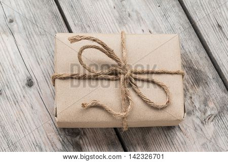 Vintage gift box brown paper wrapped with rope on wood background