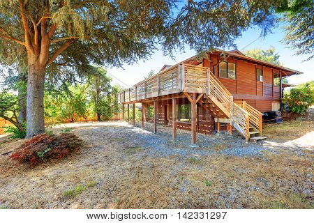 View Of Two Story House With Wooden Trim And Large Deck.