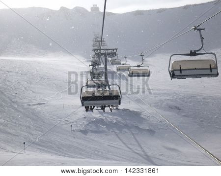 A view of a snow covered mountain with skiing from a chair lift at a ski resort in Neustift Austria.