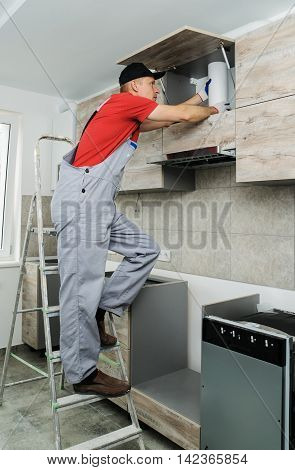 Installation of kitchen. Worker installs a pipe to a kitchen hood.