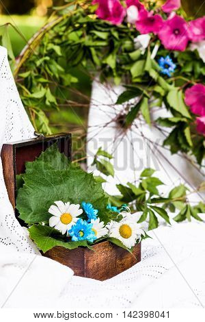 old brown box decorated with camomiles and fresh leaves in a white tablecloth