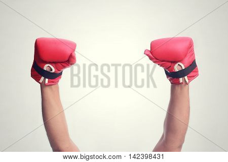 Two hands raised in the air wearing red hot boxing gloves