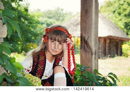 Ukrainian village. Girl in the national hutsul costume sitting with fruit