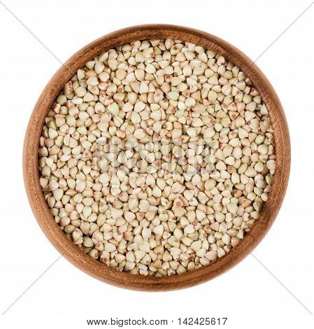 Buckwheat in a wooden bowl on white background. Small grain seeds of Fagopyrum esculentum. Edible, raw and organic food. Isolated close up macro photo.