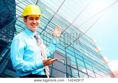 Giovane architetto indossando una standing casco protettivo sullo sfondo edificio