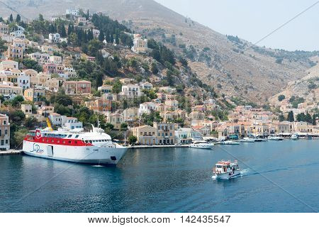 Symi Greece - August 1 2016: Panoramic image of Symi town with the harbor and the colorful houses on the hill in the Greek Island of Symi at the Aegean sea.