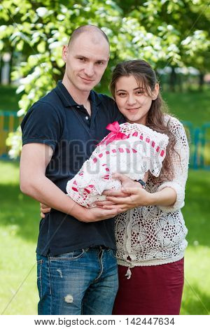 Happy Couple Holding Their Newborn Daughter In Her Arms. Outdoors