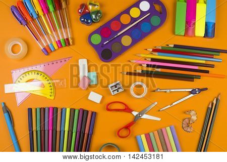 Different school supplies are on orange background.