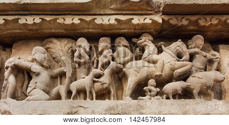 Village and rural people with animals on stone relief of Khajuraho temple India. UNESCO Heritage site built between 950 and 1150 in India belong to Hinduism and Jainism.