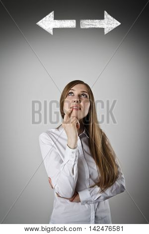 Woman in white has to decide between two directions. Girl in white full of doubts and hesitation.