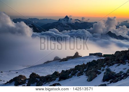 High mountain ridge in the clouds during sunrise. Beautiful panoramic landscape