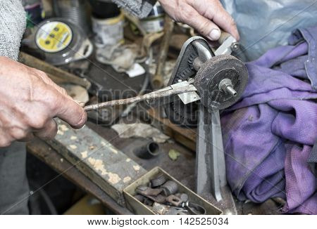 Hands of mechanic working on a retro grindstone closeup indoor shot