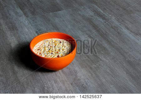 An orange bowl with milk and high protein muesli
