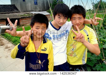 Pengzhou China - June 9 2007: Three Chinese youths flash the V sign at a Sichuan Province farm