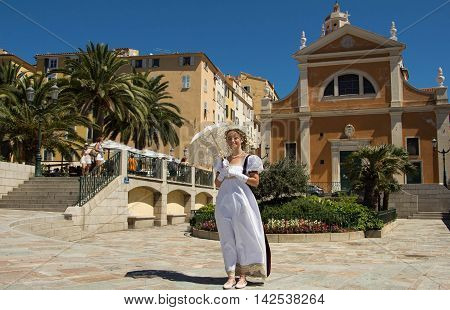 Ajaccio Corsica island France-August 14 2016: The young beautiful lady with umbrella dressed as in Napoleon's time with Our Lady of the Assumption cathedral in the background.