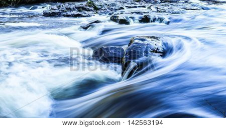 A rock in a river standing against a current at a park in Wisconsin.