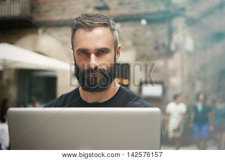 Closeup Portrait Handsome Bearded Businessman Wearing Black Tshirt Working Laptop Urban Cafe.Young Manager Work Notebook Outdoor Place.Coworking Process Business Startup.Blurred Background