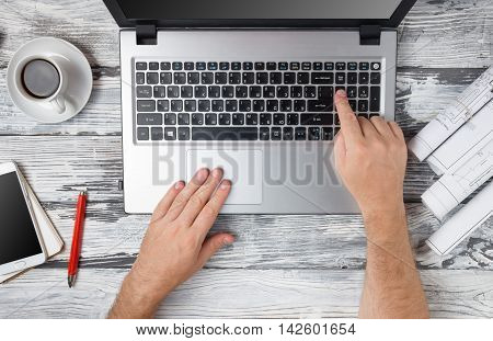 Hands typing numbers on laptop keyboard making online payment at home at the wooden table. On-line shopping concept. Selective focus. Man's hands typing on computer pc keyboard