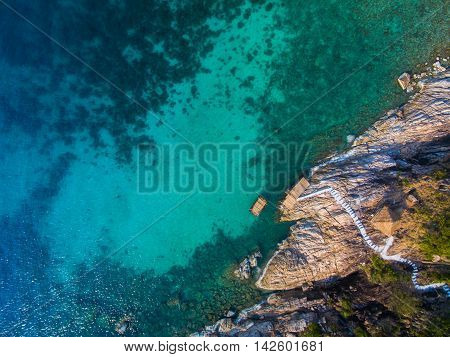 rocky coast with steps down to the turquoise water from the height of bird, Koh Phangan, Thailand