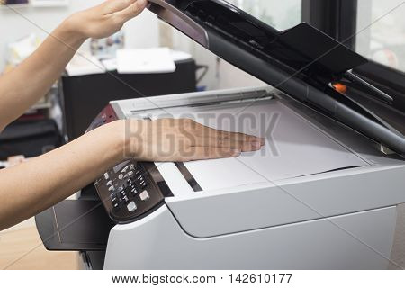 woman hands putting a sheet of paper into a copying device