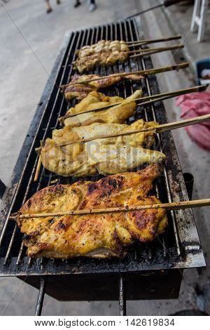 Grilling chicken plugged with bamboo on the tray